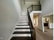 Modern staircase with dark wood steps and black rod iron railing and open floorplan at 318 Deer Tail Ln # 35, Fuquay Varina, NC 27526