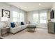 Cozy basement rec room featuring a large sectional sofa, ottoman, and two windows with custom shades at 500 Trilith Pl, Durham, NC 27713