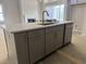 Kitchen island with stone countertop, grey cabinets, and stainless dishwasher at 63 Daybreak Way, Fuquay Varina, NC 27526