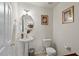 Charming half bath featuring pedestal sink, decorative mirror, and floral artwork at 634 Conover Rd, Durham, NC 27703