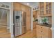 Kitchen area with stainless steel refrigerator, wooden cabinets, granite countertops, and hardwood floors at 8015 Papaya Dr, Raleigh, NC 27613