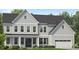Charming two-story home with a combination of white brick and vertical siding with a dark roof and black front door at 828 Timber Mist Ct, Cary, NC 27519