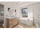 Bright bathroom featuring a modern vanity, stylish soaking tub under the window and a glass-enclosed shower at 838 Woodburn Rd, Raleigh, NC 27605