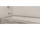 Close-up of a luxurious bathtub with a marble trim and white tiled wall with fixtures at 838 Woodburn Rd, Raleigh, NC 27605
