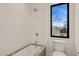 Modern bathroom features a sleek tub with a stone surround and a large window for natural light at 838 Woodburn Rd, Raleigh, NC 27605