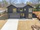A modern two-story gray home with an attached garage, well-manicured lawn, and a view of the landscape at 838 Woodburn Rd, Raleigh, NC 27605