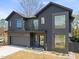 Modern home with a gray exterior featuring large windows, a two-car garage, and manicured landscaping at 838 Woodburn Rd, Raleigh, NC 27605