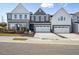 Modern townhomes with neutral siding and a two-car garage sit on a tree-lined street at 917 Montague Ave, Durham, NC 27703