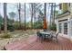 Wood deck with an outdoor dining set and an orange umbrella overlooking mature trees at 100 Burlingame Way, Cary, NC 27513