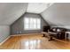 This bonus room features hardwood floors, a window with plantation shutters, and a leather couch at 100 Burlingame Way, Cary, NC 27513