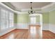 Well-lit dining room boasts wainscoting, tray ceilings, and large windows with plantation shutters at 100 Burlingame Way, Cary, NC 27513