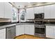 Kitchen featuring white cabinets, granite countertops, stainless steel appliances, and arched windows at 100 Burlingame Way, Cary, NC 27513