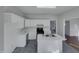 Galley kitchen with white cabinets, island, stainless steel appliances, and gray tile floor at 104 Walnut Creek Dr, Clayton, NC 27520
