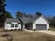 Charming single-story home with gray siding and a two-car garage, set against a backdrop of mature trees at 133 Sandcastle Ln, Four Oaks, NC 27524