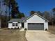 Single-story home with gray siding and a two-car garage, complemented by a well-manicured lawn at 133 Sandcastle Ln, Four Oaks, NC 27524