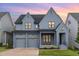Beautiful, two-story home featuring gray siding, black trim, two-car garage, and charming front porch at sunset at 183 Post Oak Rd, Chapel Hill, NC 27516
