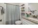 This bathroom features a neutral shower curtain, stylish shelves with decor, and a well-lit vanity area at 202 W Hill St, Benson, NC 27504