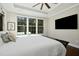 Bright main bedroom featuring hardwood floors, a ceiling fan, and large windows overlooking lush green backyard at 2515 Maplemere Ct, Durham, NC 27703