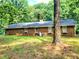 Brick home showcasing a backyard, complete with mature trees and plenty of space for recreation and relaxation at 323 Ranch Farm Rd, Raleigh, NC 27603