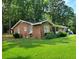 Charming brick home nestled on a lush green lawn, surrounded by mature trees, creating a peaceful and private setting at 323 Ranch Farm Rd, Raleigh, NC 27603