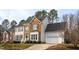Charming home showcasing a two-car garage and brick facade, set amidst lush greenery at 3528 Dewing Dr, Raleigh, NC 27616