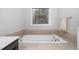 Relaxing bathroom features a large soaking tub with tiled surround and a large window at 357 Roberts Ridge Dr, Cary, NC 27513