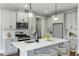 The kitchen boasts modern white cabinets, stainless steel appliances, a quartz island with seating and pendant lights at 73 Merle Dr, Wendell, NC 27591