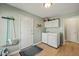 Bright laundry room with washer, dryer, overhead cabinets and wood-look floors at 11424 Horsemans Trl, Raleigh, NC 27613