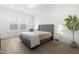 Bright bedroom with a gray upholstered bed, hardwood floors, and a view through a window at 124 Ferrell W Rd, Apex, NC 27523