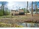 Tan two-story home featuring a wood deck, small backyard stream, and mature trees at 14 Winchester Ct, Durham, NC 27707
