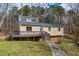 Charming, tan home with a deck, a walkway, and windows under a cloudy blue sky at 14 Winchester Ct, Durham, NC 27707