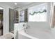 Well-lit bathroom featuring a soaking tub, walk-in shower, and a window offering serene views at 1404 Vanguard Pl, Durham, NC 27713