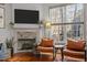 Cozy living room featuring a fireplace, hardwood floors, large windows, and comfortable leather seating at 1404 Vanguard Pl, Durham, NC 27713