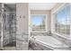 Bright bathroom featuring tiled shower and soaking tub with a large window at 1421 Harvey Johnson Rd, Raleigh, NC 27603