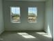 A carpeted bedroom featuring two windows that reveal ongoing construction outside at 1573 Wendell Valley Blvd, Wendell, NC 27591