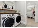Laundry room with modern washer and dryer, wooden shelves, and access to the walk-in closet at 1737 Fence Post Rd, Wendell, NC 27591