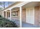 Inviting front porch with white columns and railing, showcasing the brick exterior and shuttered storage at 2201 Knollwood Dr, Sanford, NC 27330