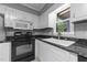 Close up on the kitchen featuring black appliances, granite countertops, and white cabinetry at 2301 Pastille Ln, Raleigh, NC 27612