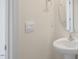 Cozy powder room featuring a pedestal sink, round mirror, and modern light switch at 292 Perseus St, Angier, NC 27501