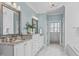 Double vanity with granite countertop, white cabinets, and an adjacent bathtub at 5025 Fanyon Way, Raleigh, NC 27612