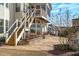 Home's backyard featuring patio, stone retaining wall, stairs to upper porch, and partial view of house at 5025 Fanyon Way, Raleigh, NC 27612
