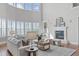 Bright living room features soaring windows, a cozy fireplace, and ample seating for entertaining at 5025 Fanyon Way, Raleigh, NC 27612