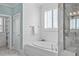 Bright bathroom featuring shiplap, a soaking tub, and a separate shower with a glass door at 5025 Fanyon Way, Raleigh, NC 27612