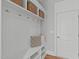 Mudroom features built-in bench with coat hooks, storage shelves, three wicker baskets, and hardwood floors at 5025 Fanyon Way, Raleigh, NC 27612