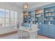 Home office features custom blue built-in shelving, modern decor, and ample natural light at 5025 Fanyon Way, Raleigh, NC 27612