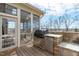 Outdoor kitchen equipped with a grill, mini fridge, stone counter, and screened patio at 5025 Fanyon Way, Raleigh, NC 27612