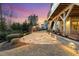 Inviting stone patio featuring an outdoor fireplace and landscape lighting, ideal for evening gatherings at 5025 Fanyon Way, Raleigh, NC 27612