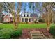 View of brick home with a manicured lawn and trees framing the front at 5300 Grand Gate Dr, Raleigh, NC 27613