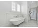 Elegant white bathroom featuring a clawfoot tub, marble floors, and plenty of natural light from the window at 543 Guilford Cir, Raleigh, NC 27608
