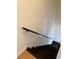 Stairway with dark wood stairs and a light-colored wall featuring a wooden handrail for safety and support at 6102 Highcastle Ct, Raleigh, NC 27613
